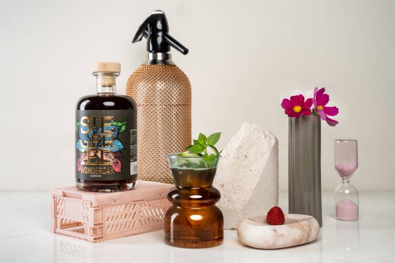Wonderoak alkoholfrei in einer stylischen Flasche mit der Aufschrift "Siegfried", ein Glas mit Minze und andere Accessoires