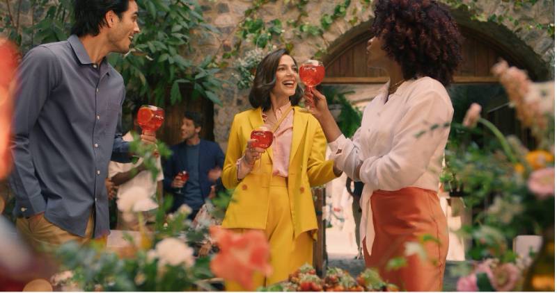 Junge Leute feiern eine Open-Air-Party vor einem antiken Gebäude mit Rundbögen.