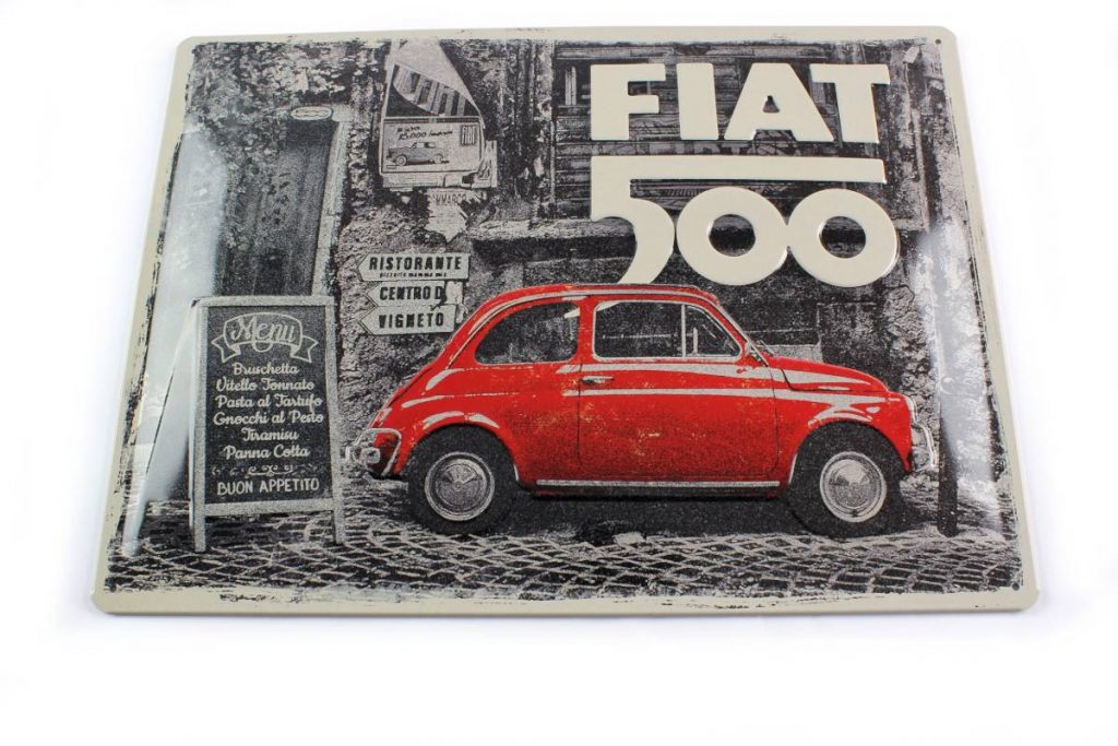 Auf einem Vintage-Blechschild in den Farben Schwarz, Grau, Rot und Weiß ist ein Fiat 500 zu sehen. Er parkt vor einem alten rustikalen Haus, das vermutlich ein Restaurant beherbergt.
